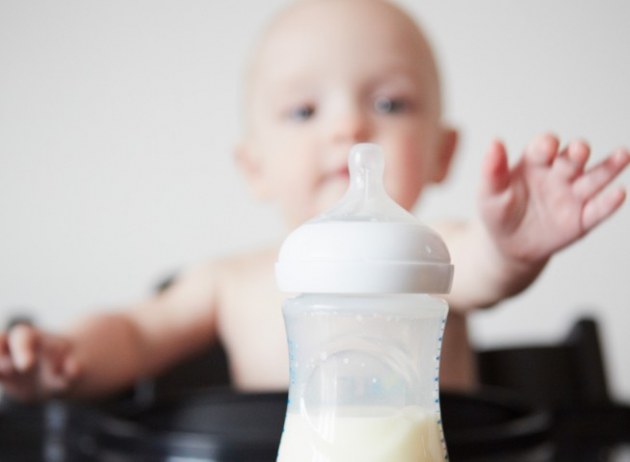 Baby greift nach einer Milchflasche