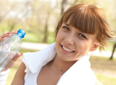 Frau mit Wasserflasche und Handtuch um den Hals