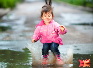 Kind springt im Regenwasser