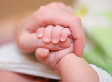 Kleines Babyhaendchen in einer grossen Hand