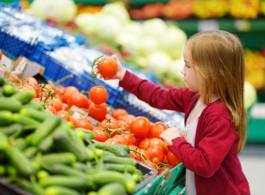 Mädchen wählt Gemüse im Supermarkt aus