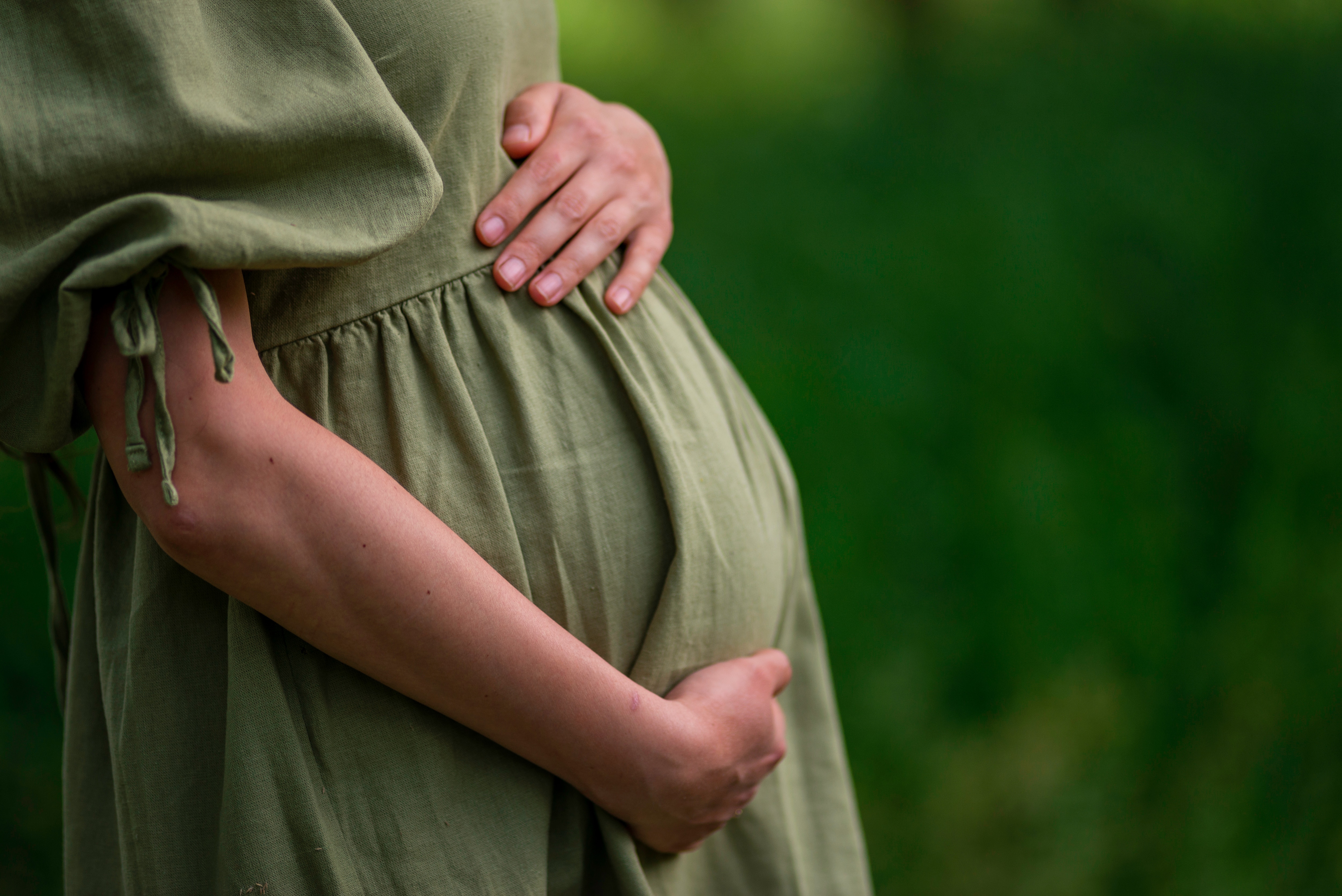 Schwangere Frau hält sich den Bauch