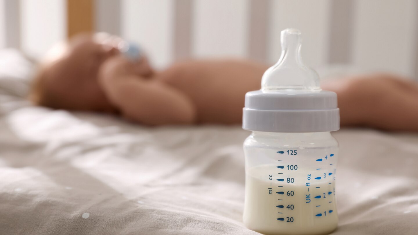 baby liegt im hintergrund milchflasche steht im vordergrund