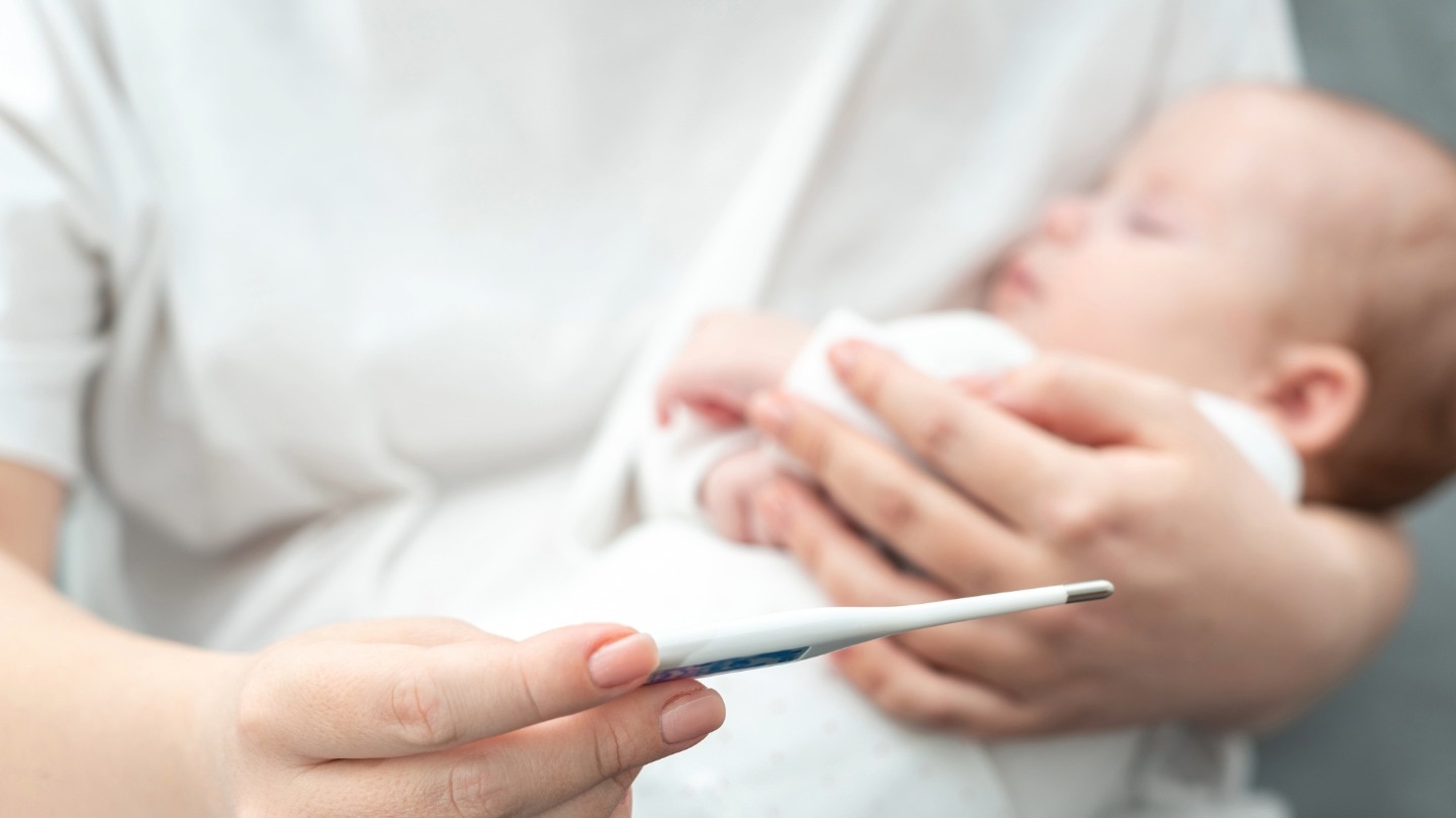 mama mit baby und fieberthermometer