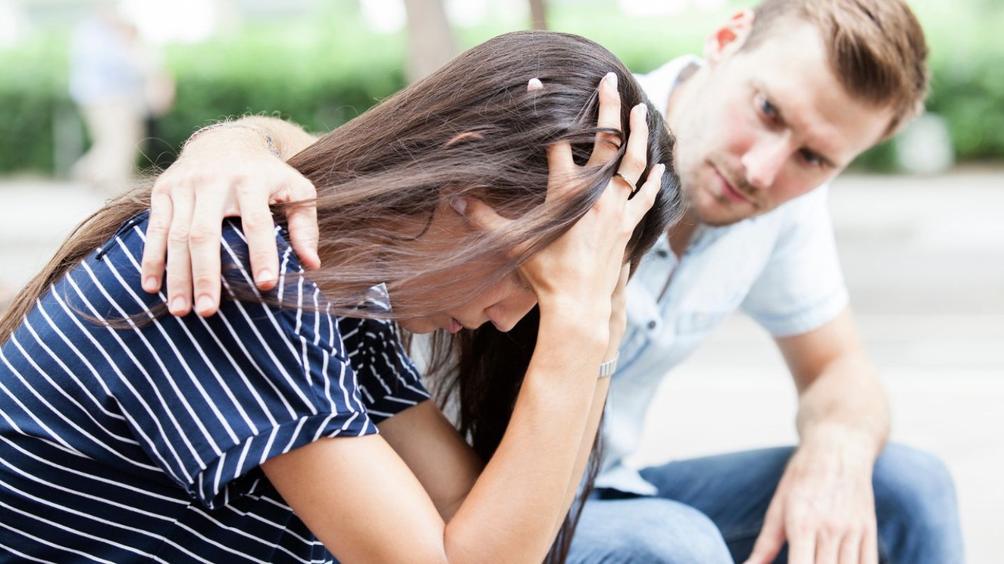 mann tröstet eine frau auf einer parkbank