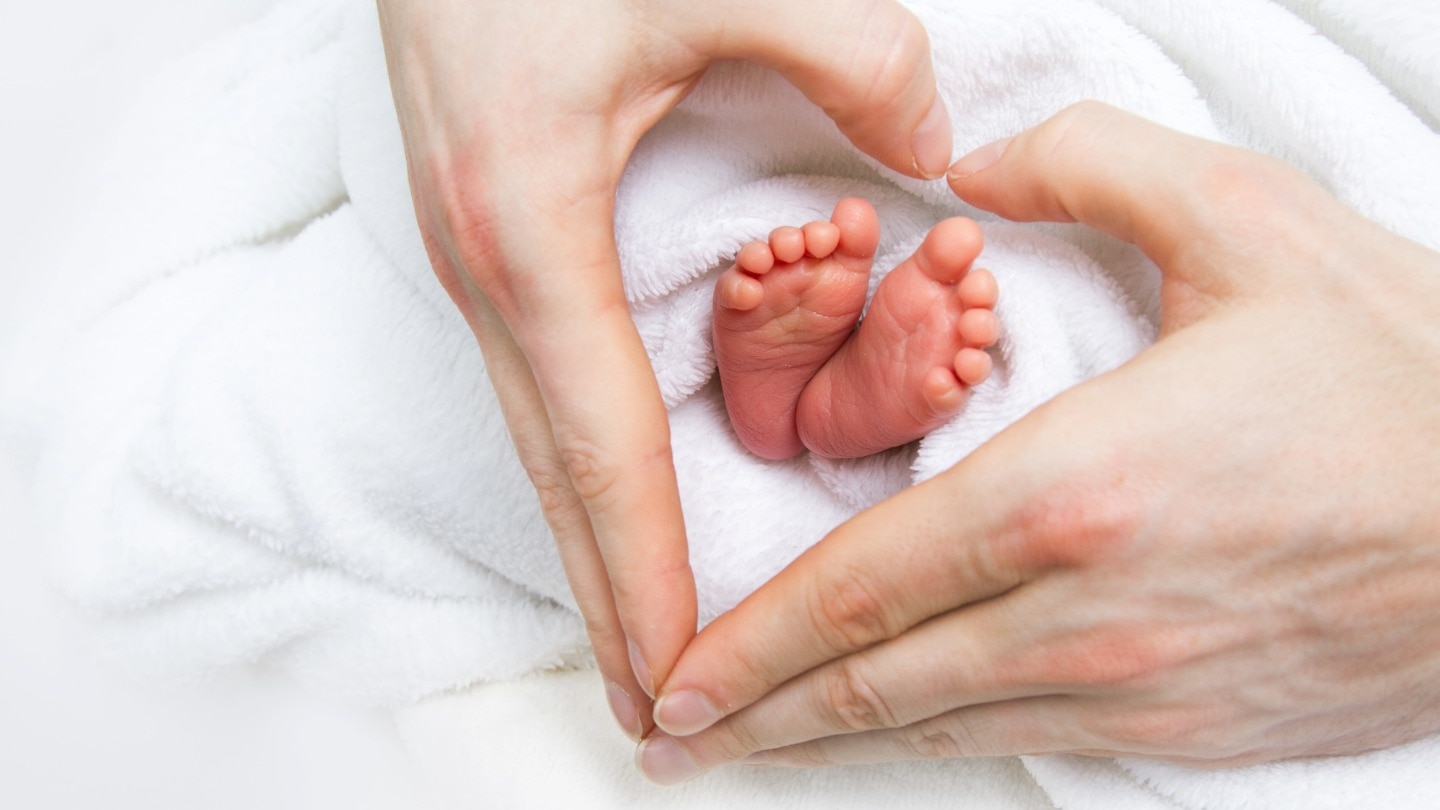 kleine babyfüßchen und hände formen ein herz