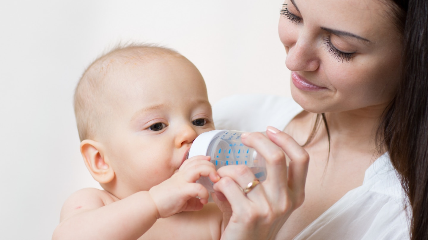 happy mother feeds her baby from bottle