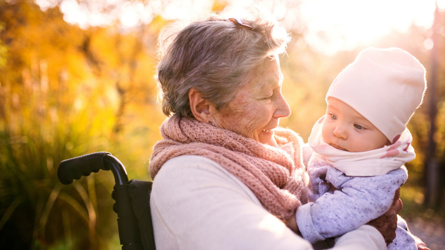 elderly woman in wheelchair with baby in autumn nature