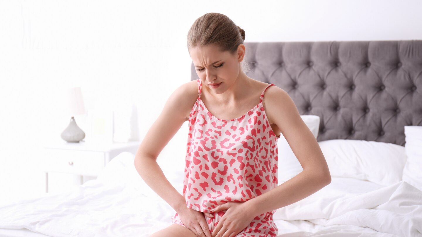 Young woman suffering from menstrual cramps at home