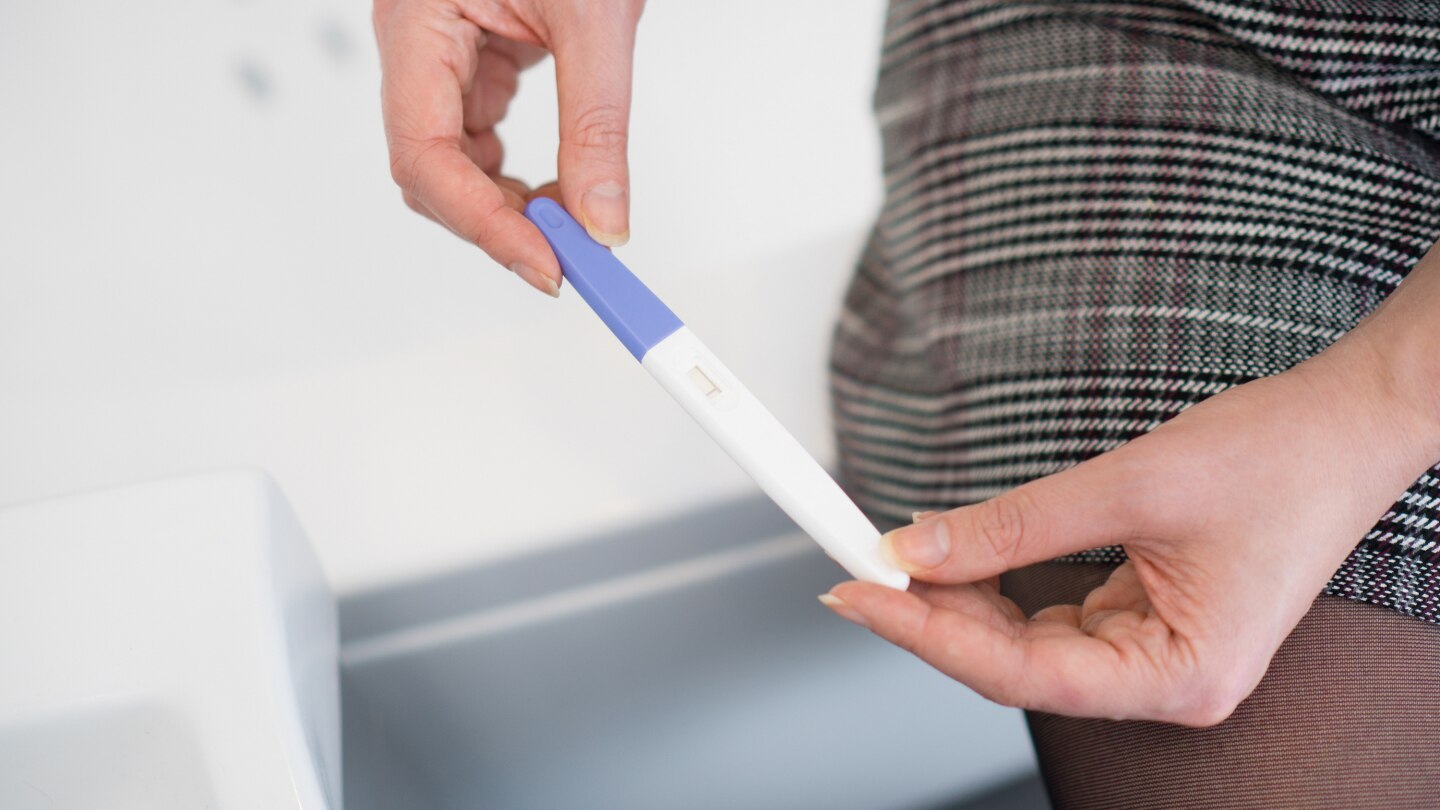 Woman with negative pregnancy test sitting in the bathroom
