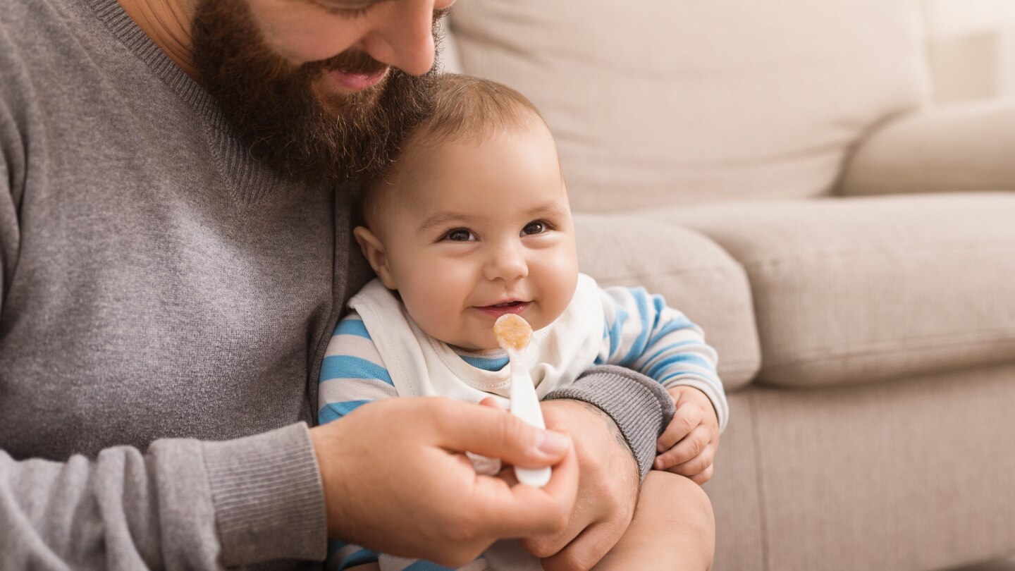 Father feeding his cute baby son at home