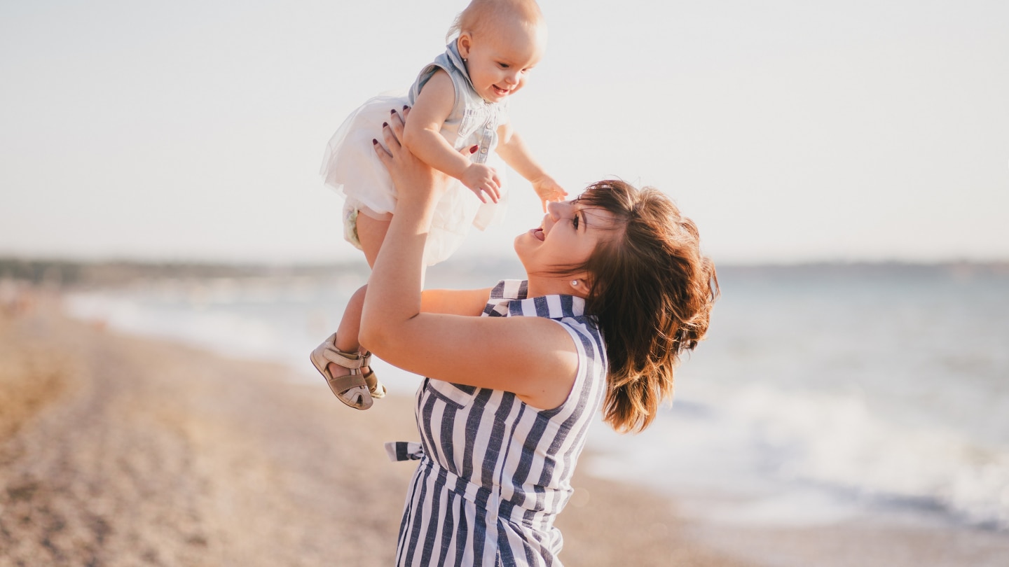 Happy mother and baby daughter posing near sea