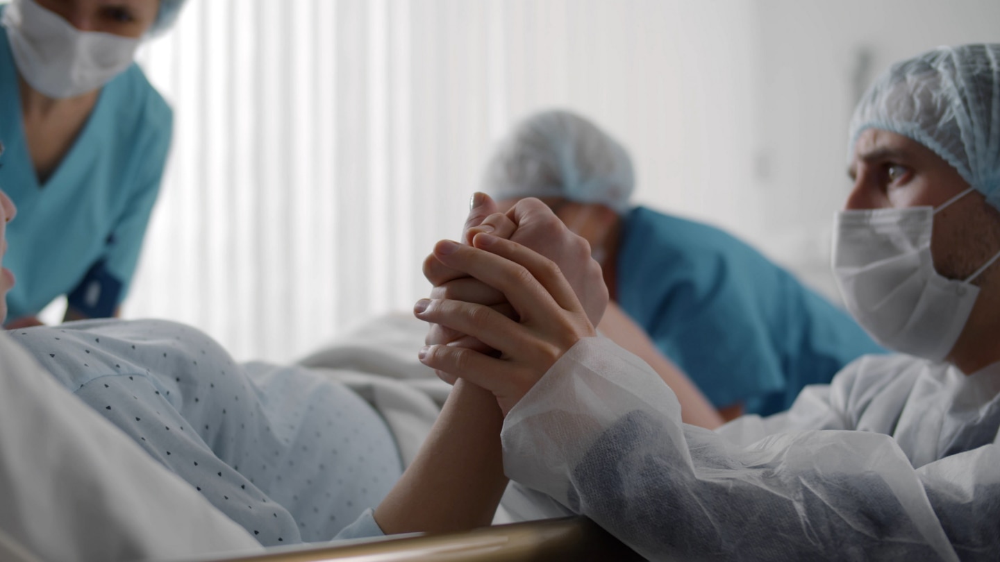 Mann hält Hand bei der Geburt