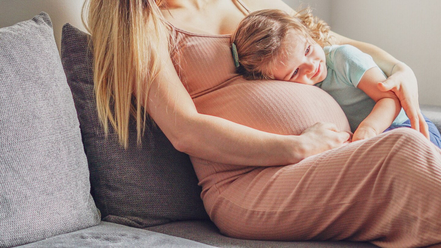 girl relaxing on mom's pregnant belly