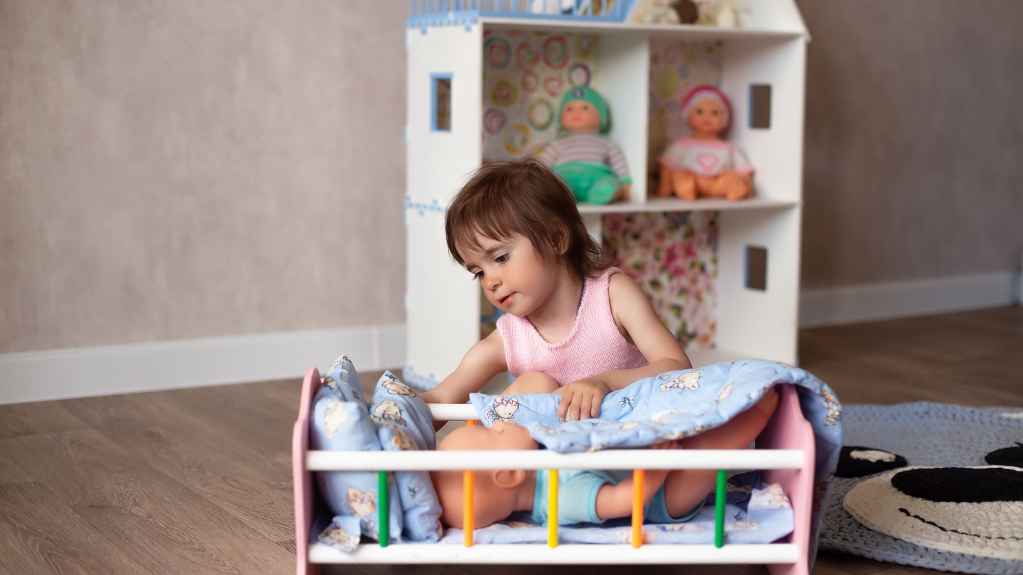Cute little girl is playing with a doll at home