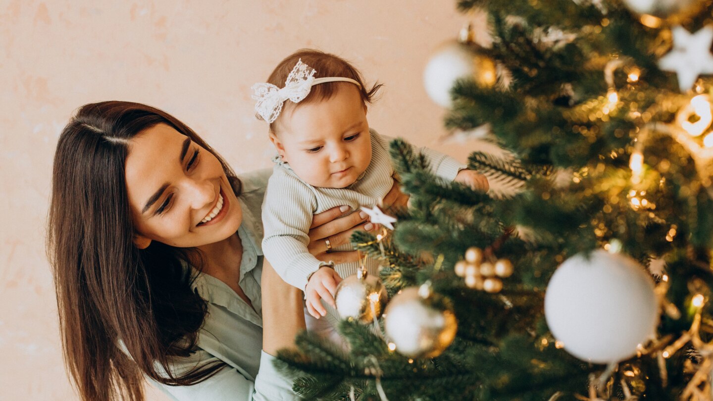 Mutter und Baby schmücken den Weihnachtsbaum