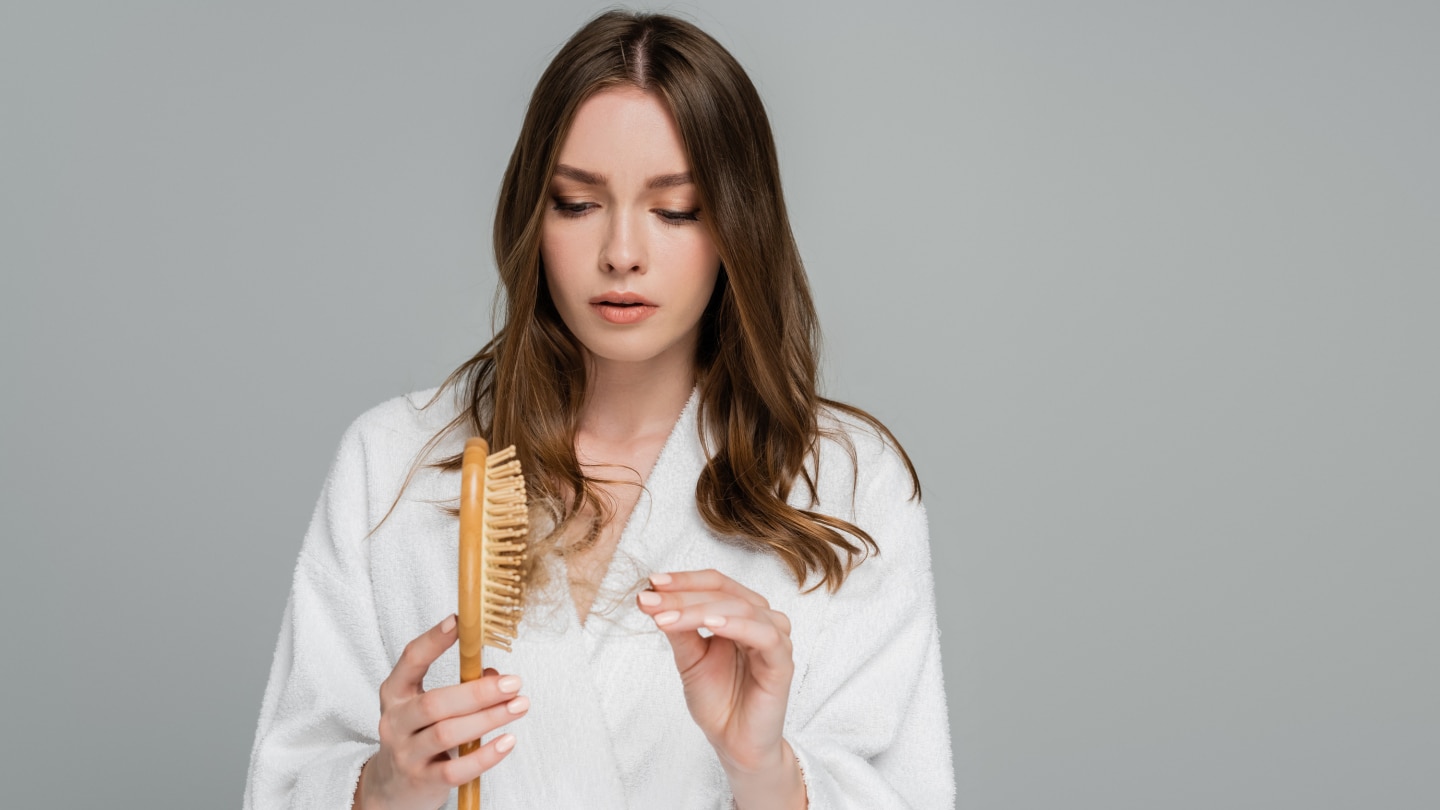 stressed young woman holding wooden hair brush