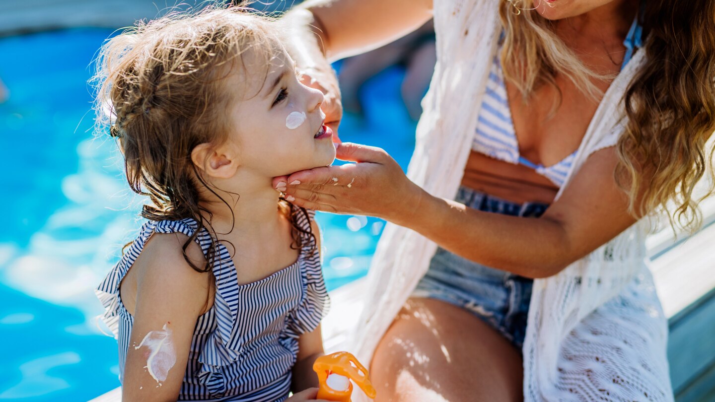 Kind wird mit Sonnencreme eingecremt