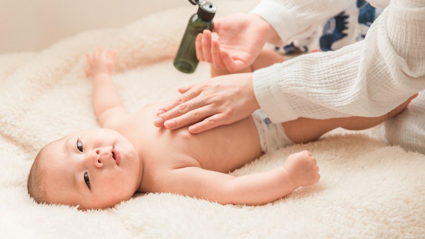 Mutter schmiert ihn mit Babyöl ein