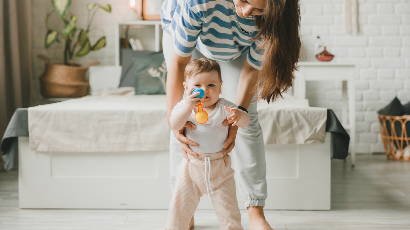 little child learns to walk with the help of mother at home