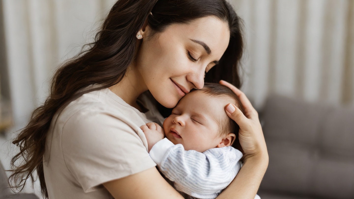 happy mum holding sleeping infant child on hands