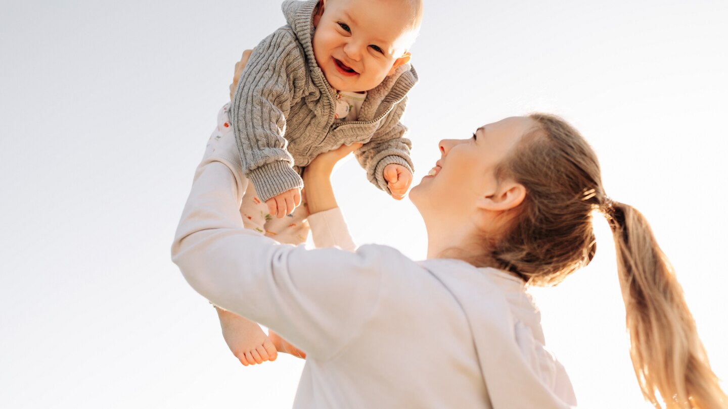 mama hält baby hoch in die luft