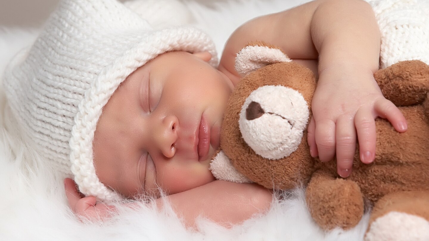 schlafendes neugeborenes mit teddy im arm