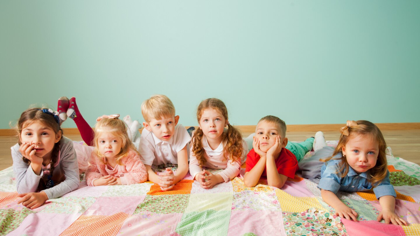 viele kinder liegen nebeneinander auf dem einer decke auf dem boden