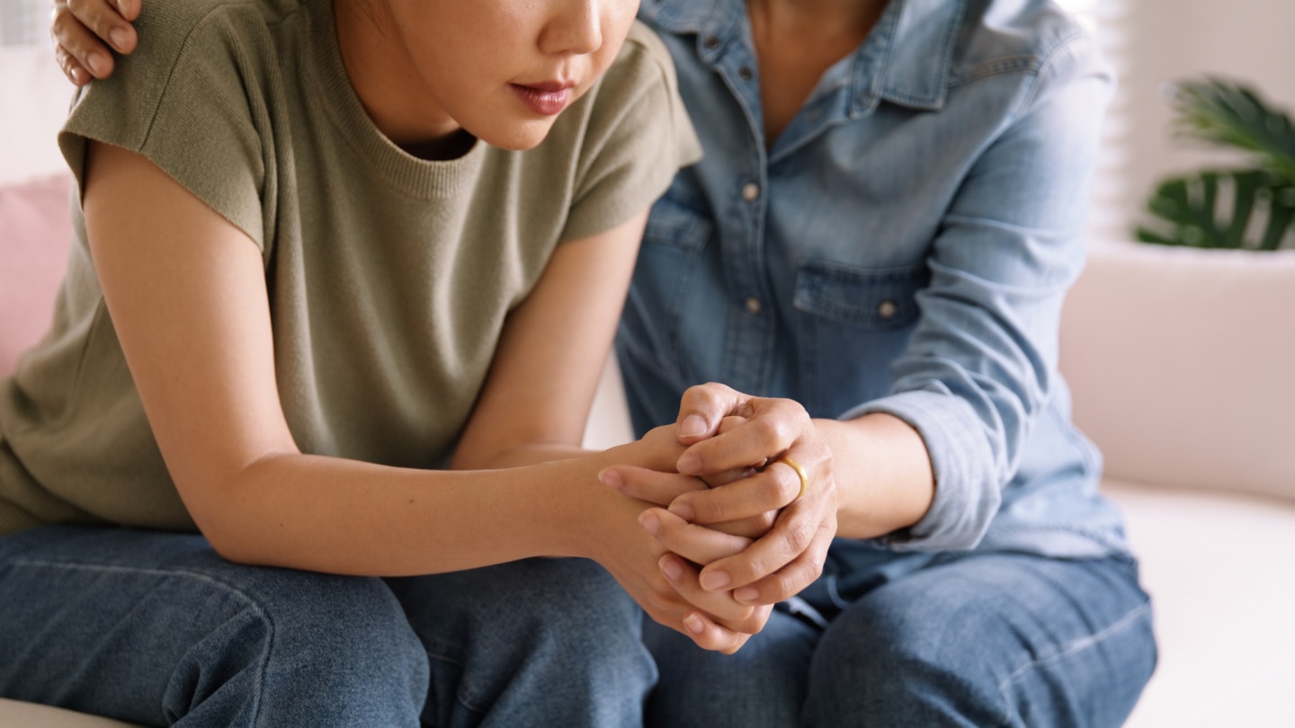 mutter und tochter sitzen besorgt zusammen