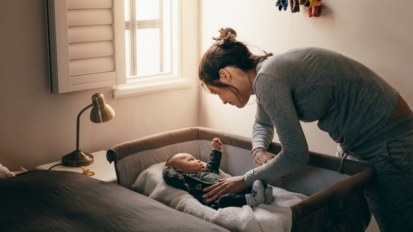 mutter-legt-baby-in-das-beistellbett