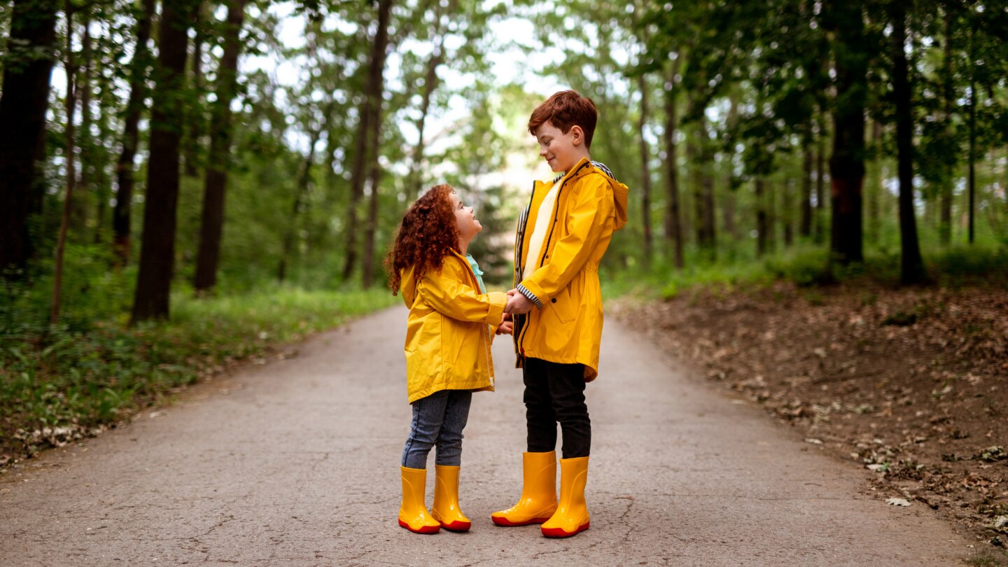 bruder-und-schwester-in-gelben-regenjacken-im-wald