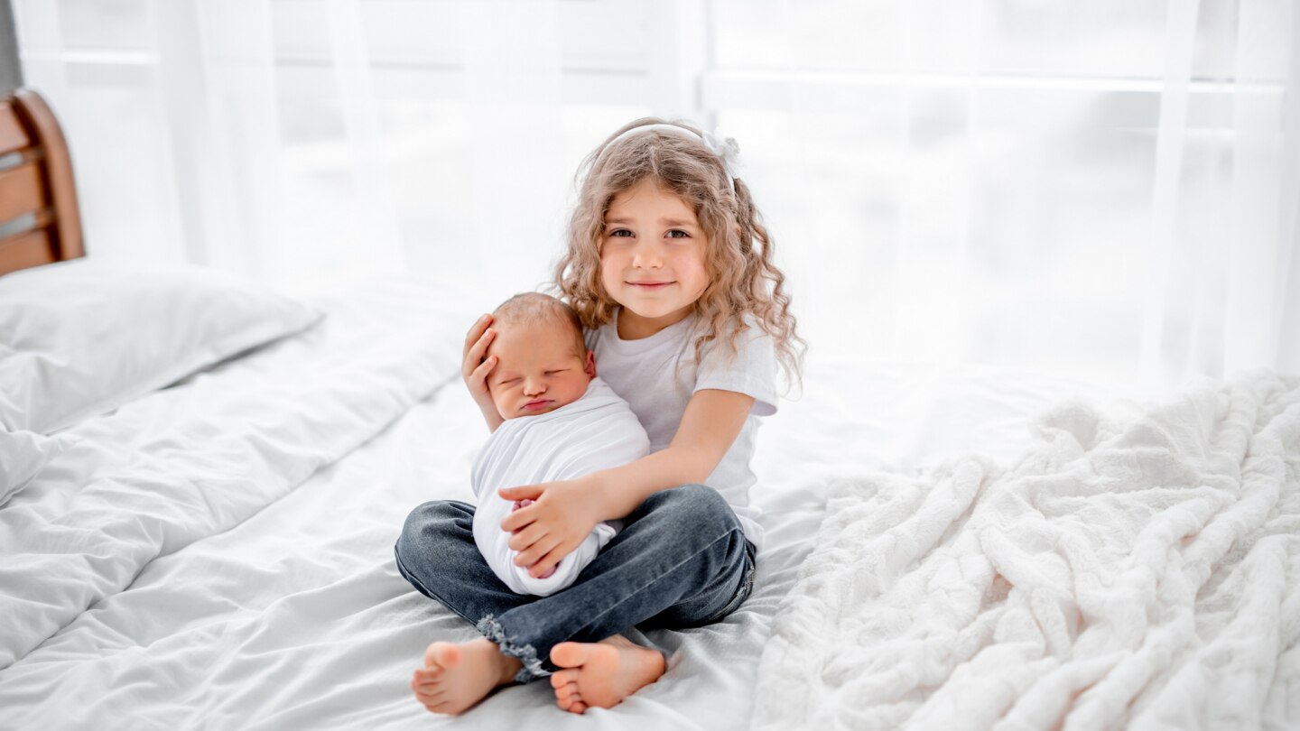 große-schwester-hält-baby-im-arm