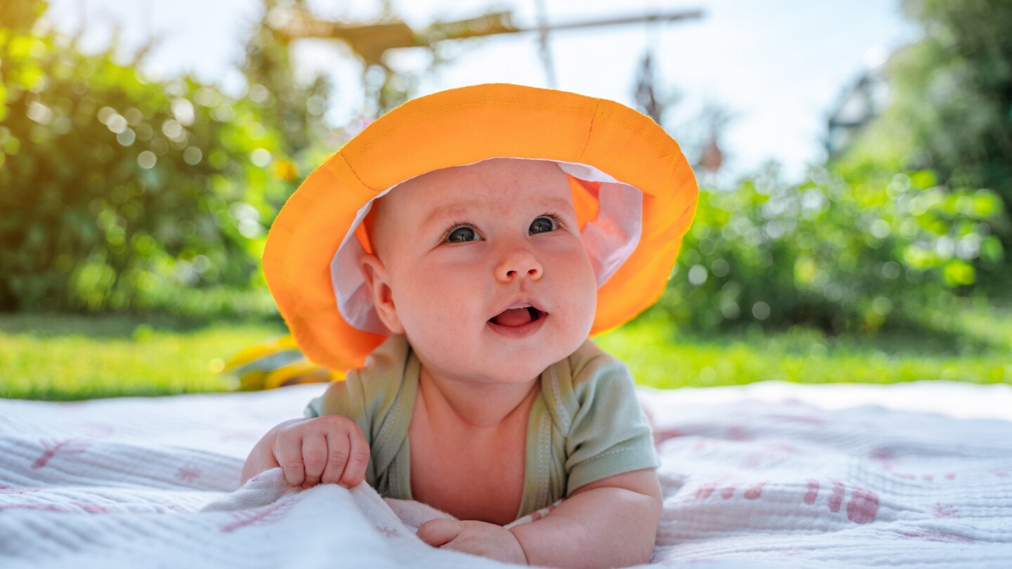 baby-mit-sonnenhut-auf-wiese