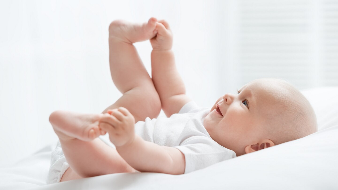 baby-liegt-auf-dem-rücken-und-spielt-mit-seinen-füßen