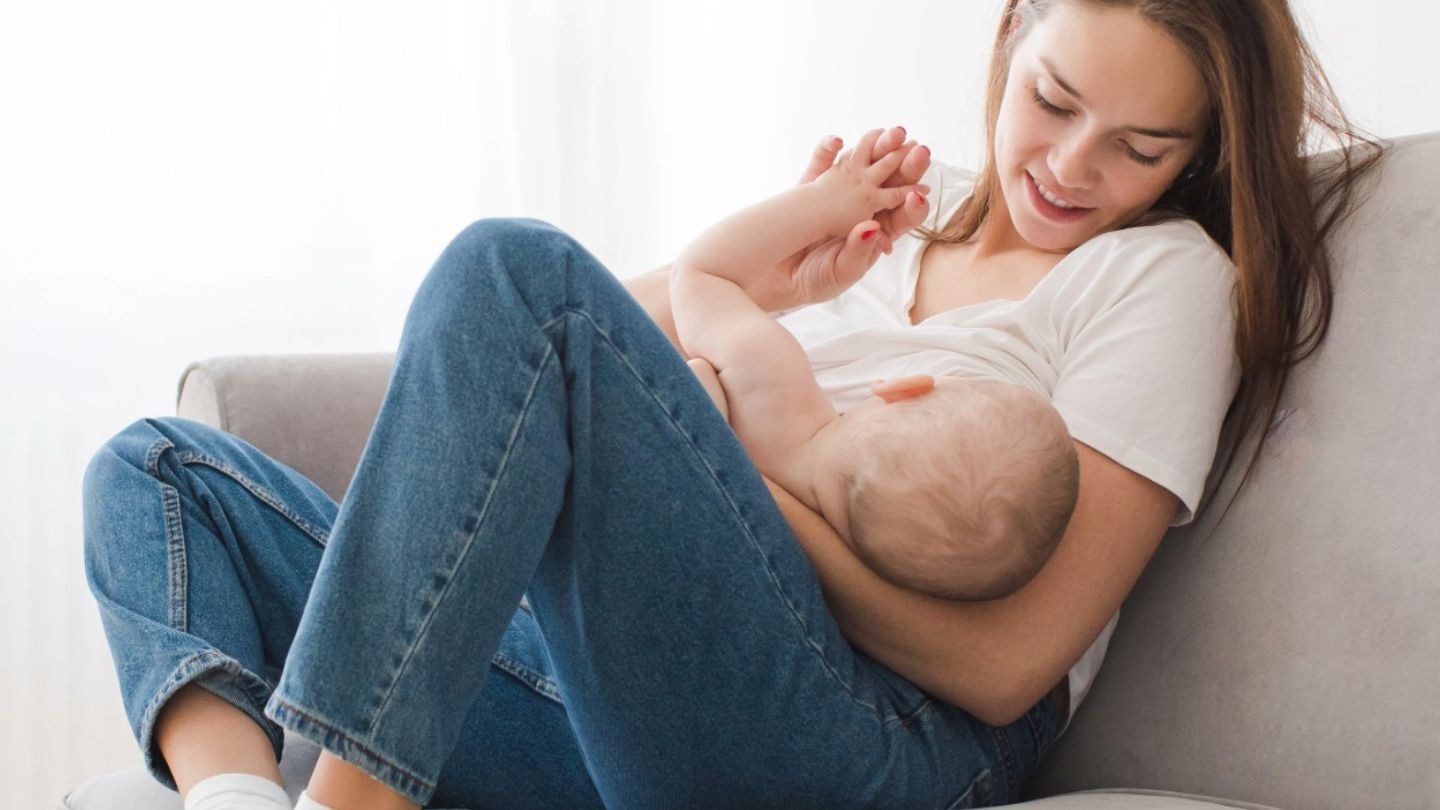 mama stillt ihr baby auf der couch