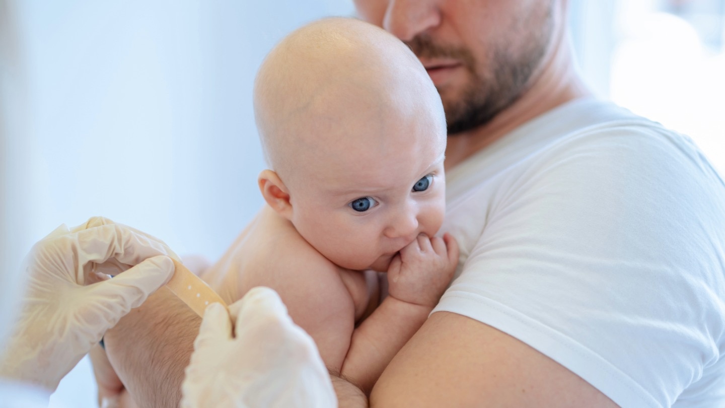 baby auf papas arm hat eine impfung bekommen