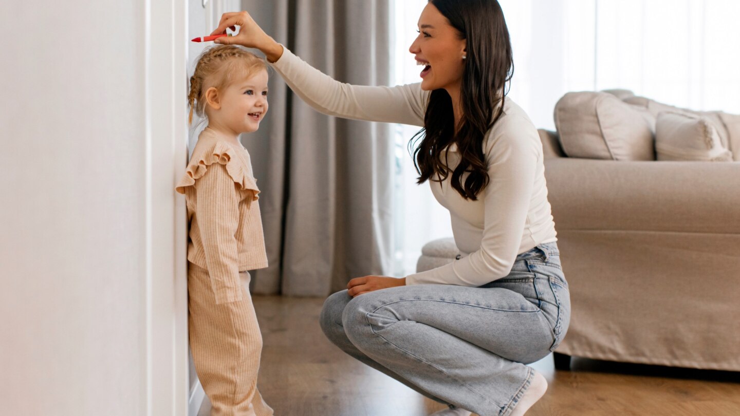mama misst körpergröße ihrer tochter an der wand