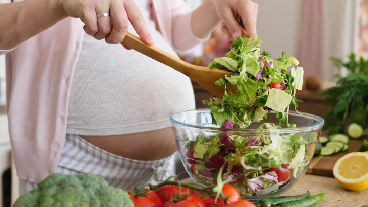 schwangere bereitet einen salat zu