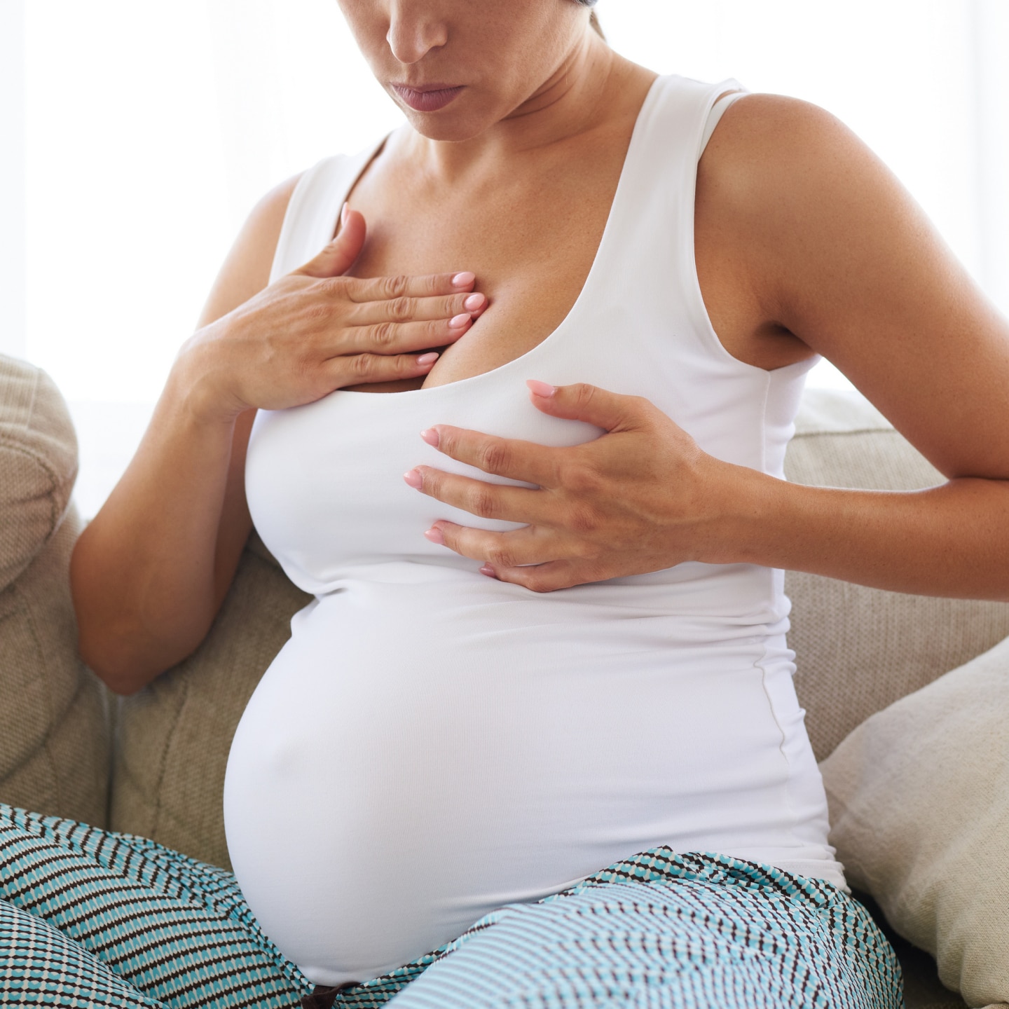 Schwangere fasst ihre Brust an