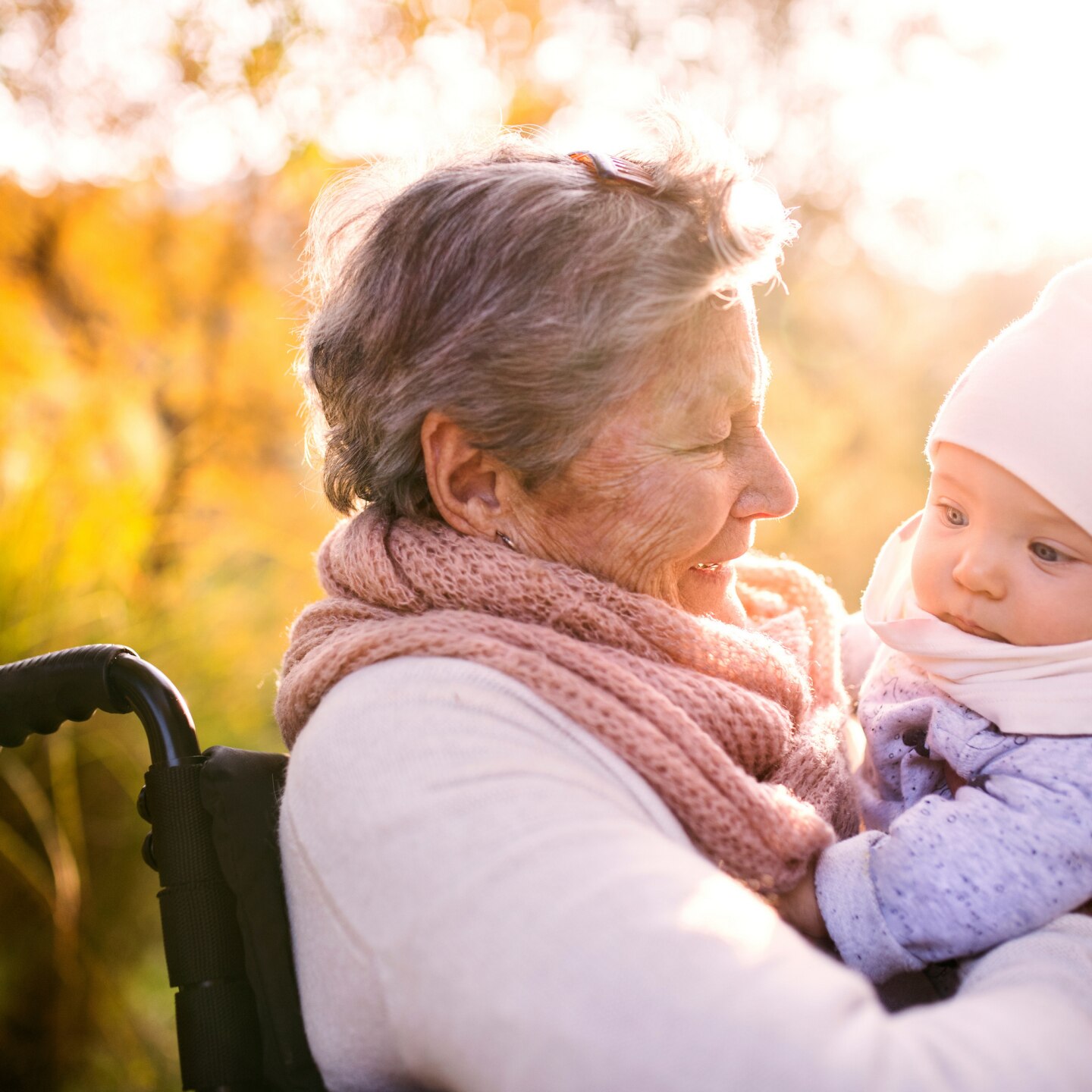 elderly woman in wheelchair with baby in autumn nature