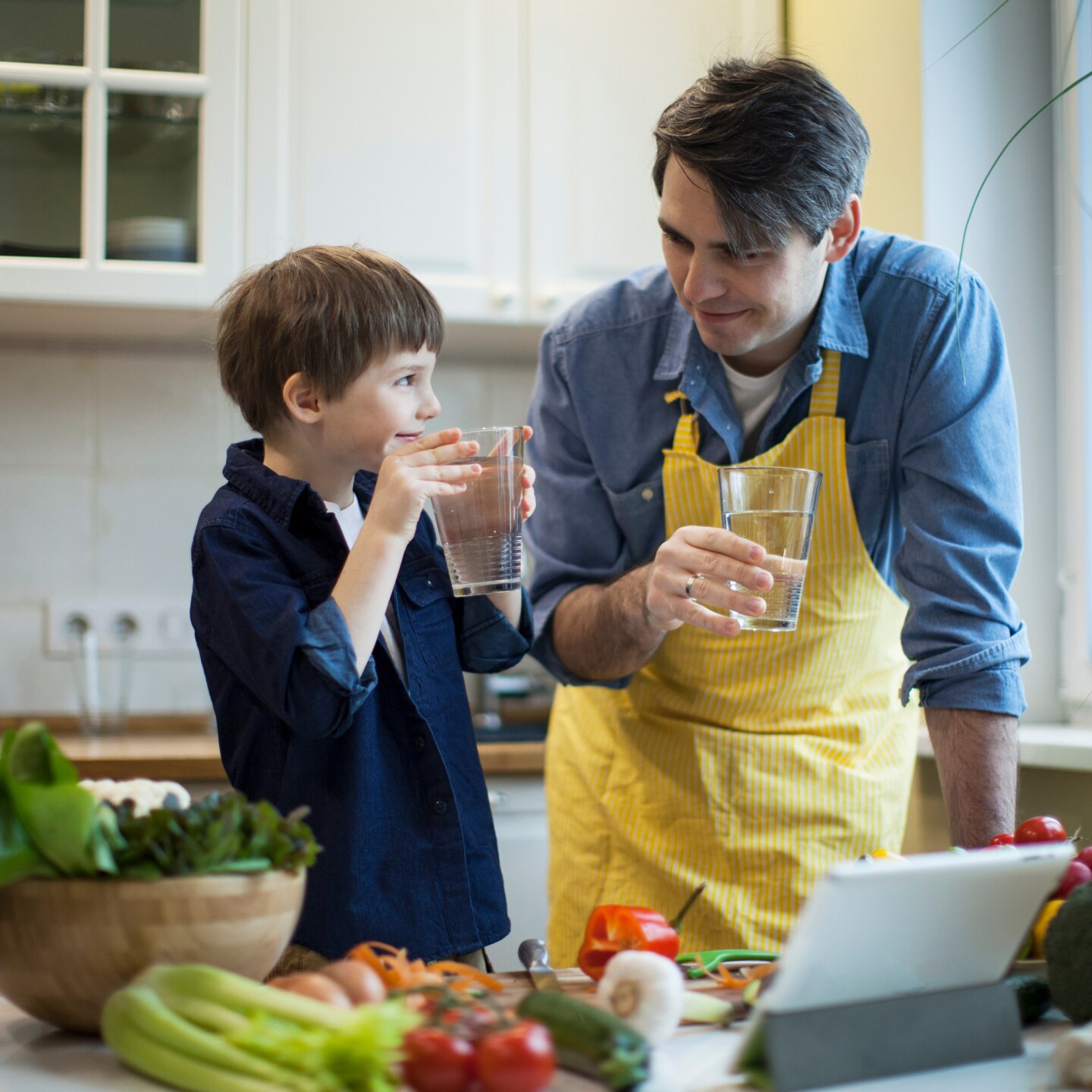 Vater und Sohn trinken Glas Wasser beim kochen