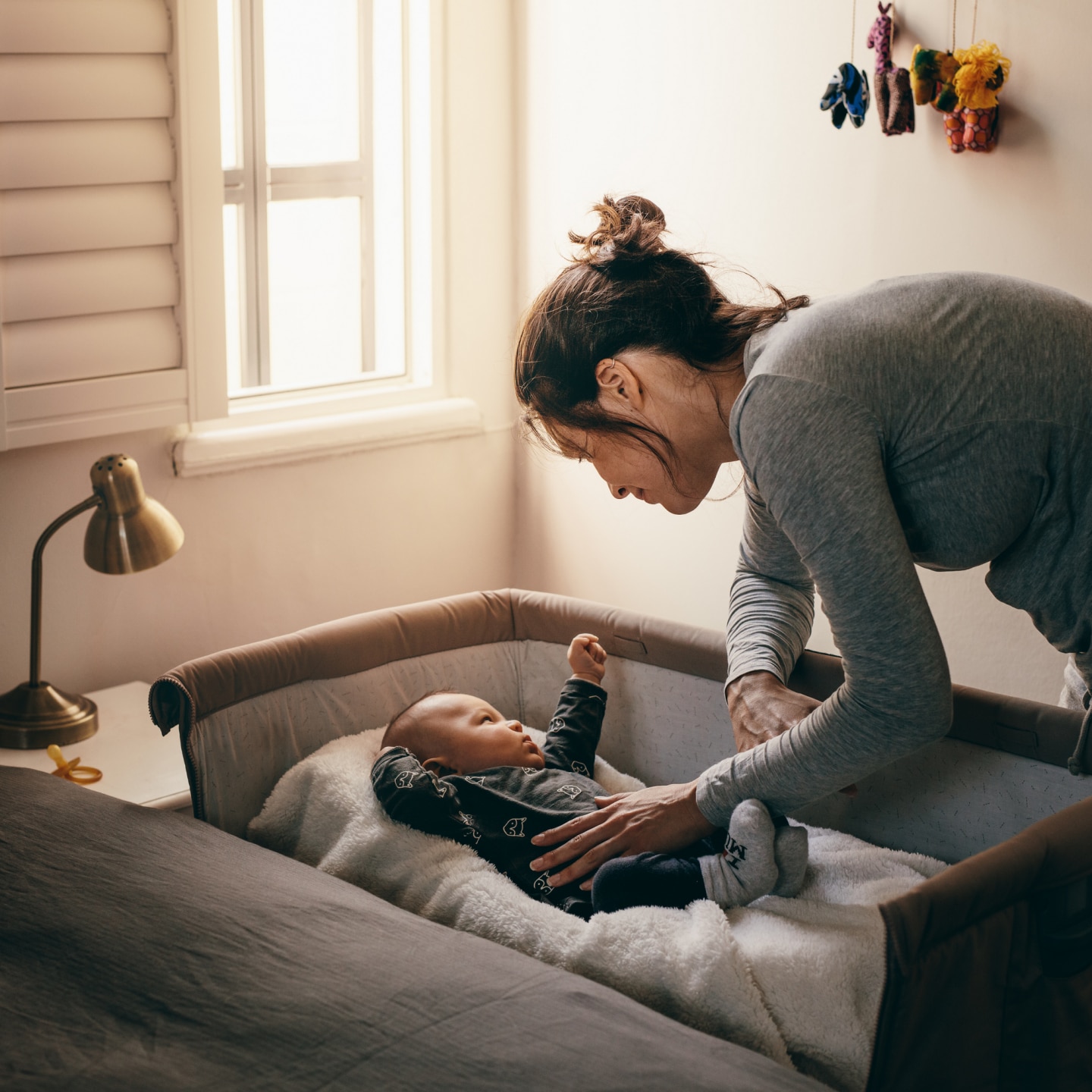 Young mother looking at her baby sleeping in a crib