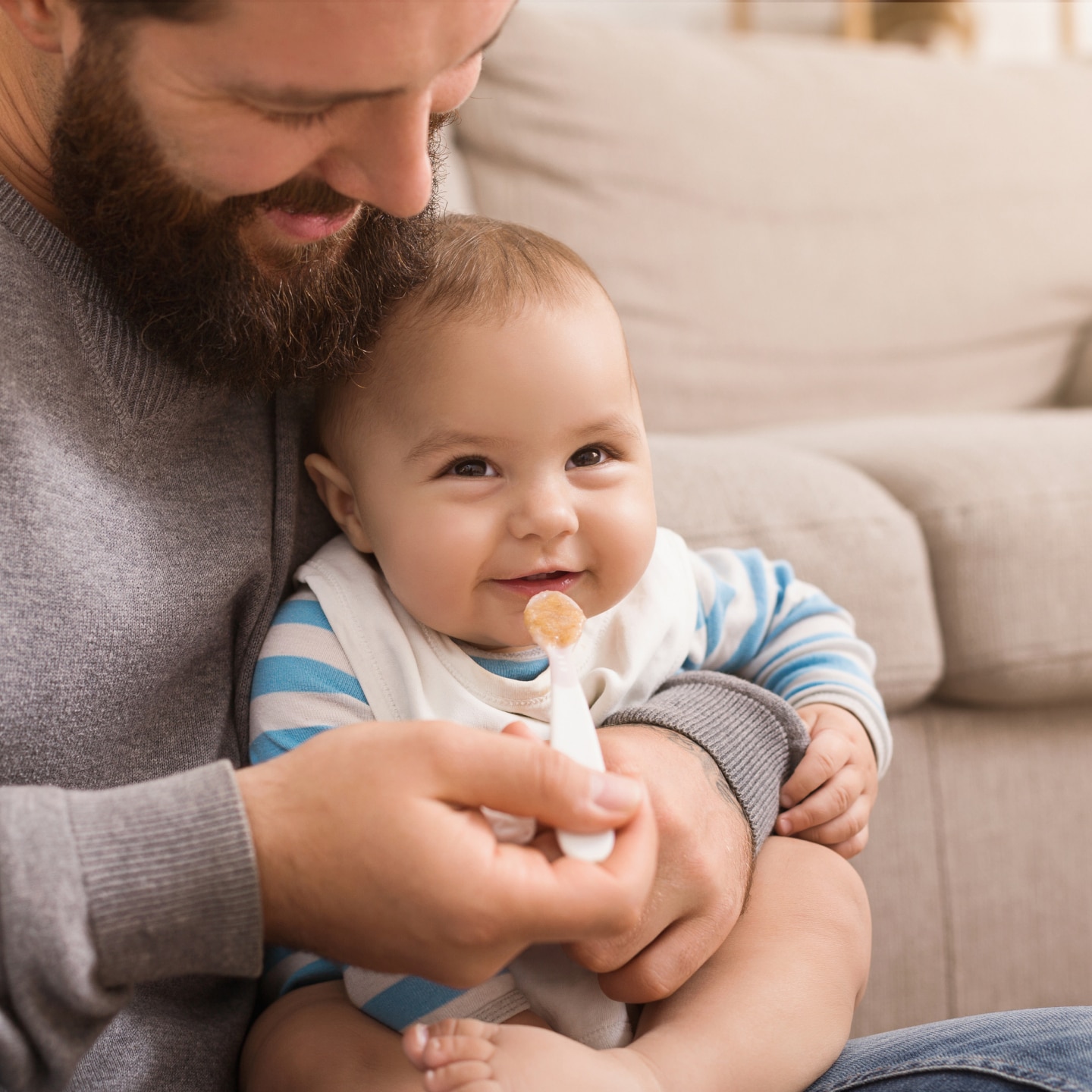 Father feeding his cute baby son at home