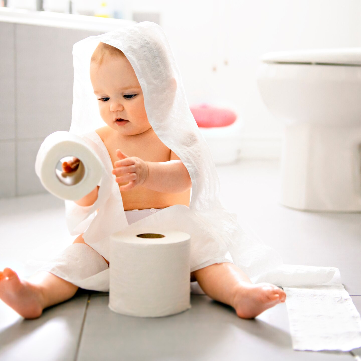 Toddler ripping up toilet paper in bathroom