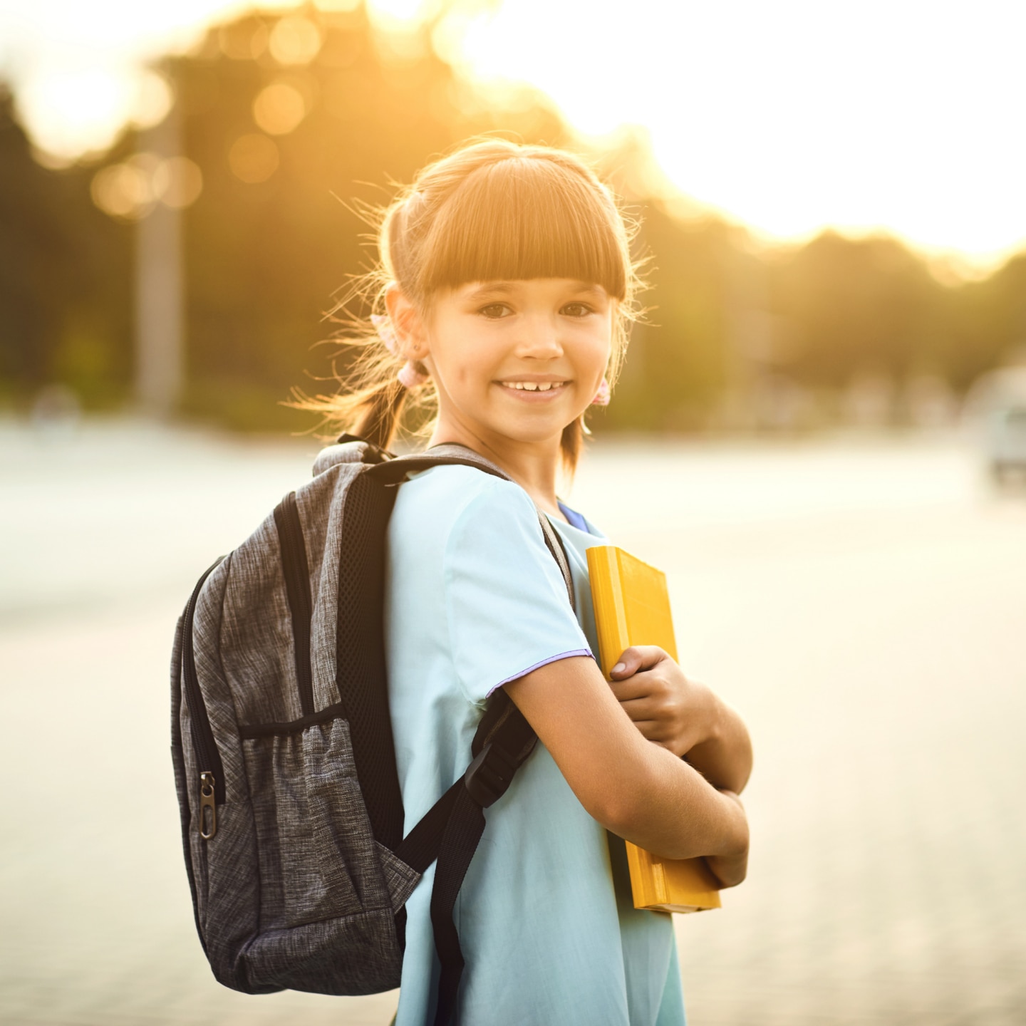 Happy little student girl with a backpack on her way to school