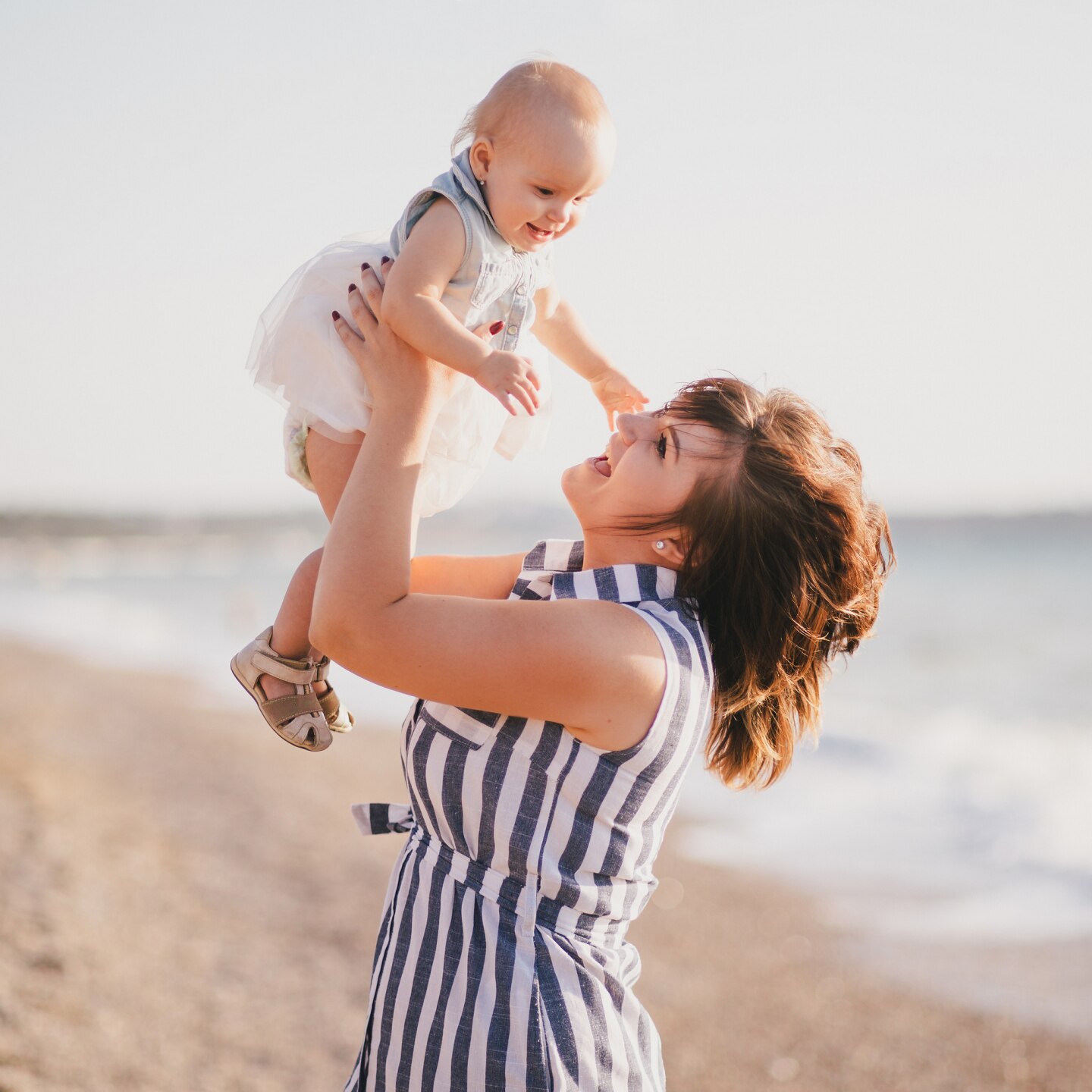Happy mother and baby daughter posing near sea