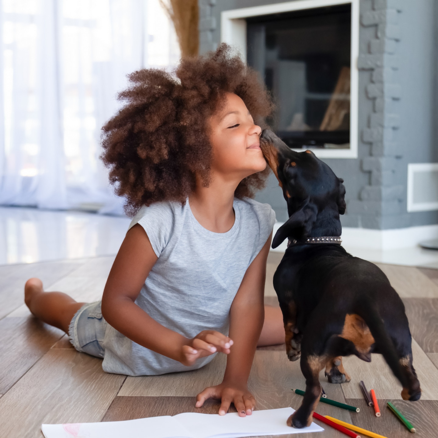 Cute little girl lying on floor playing with dog