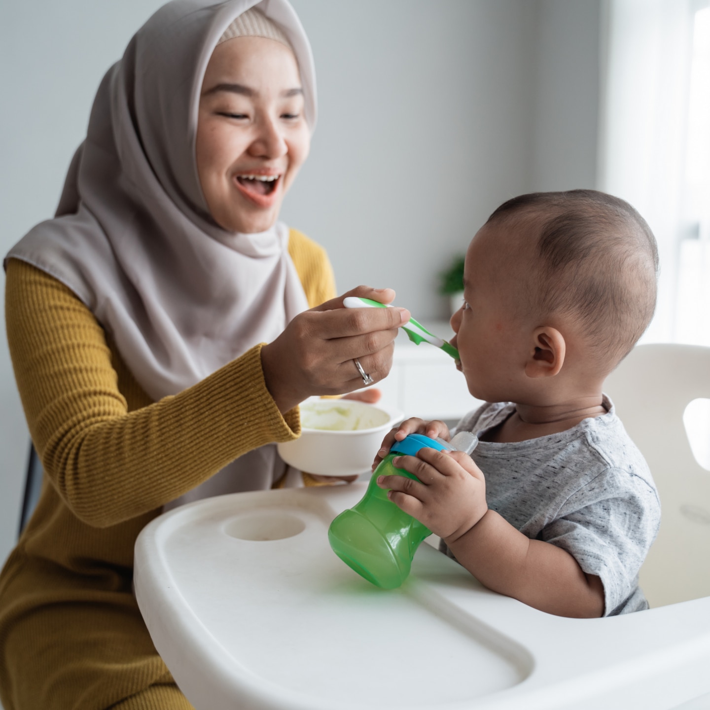 muslim asian mother feeding her baby boy