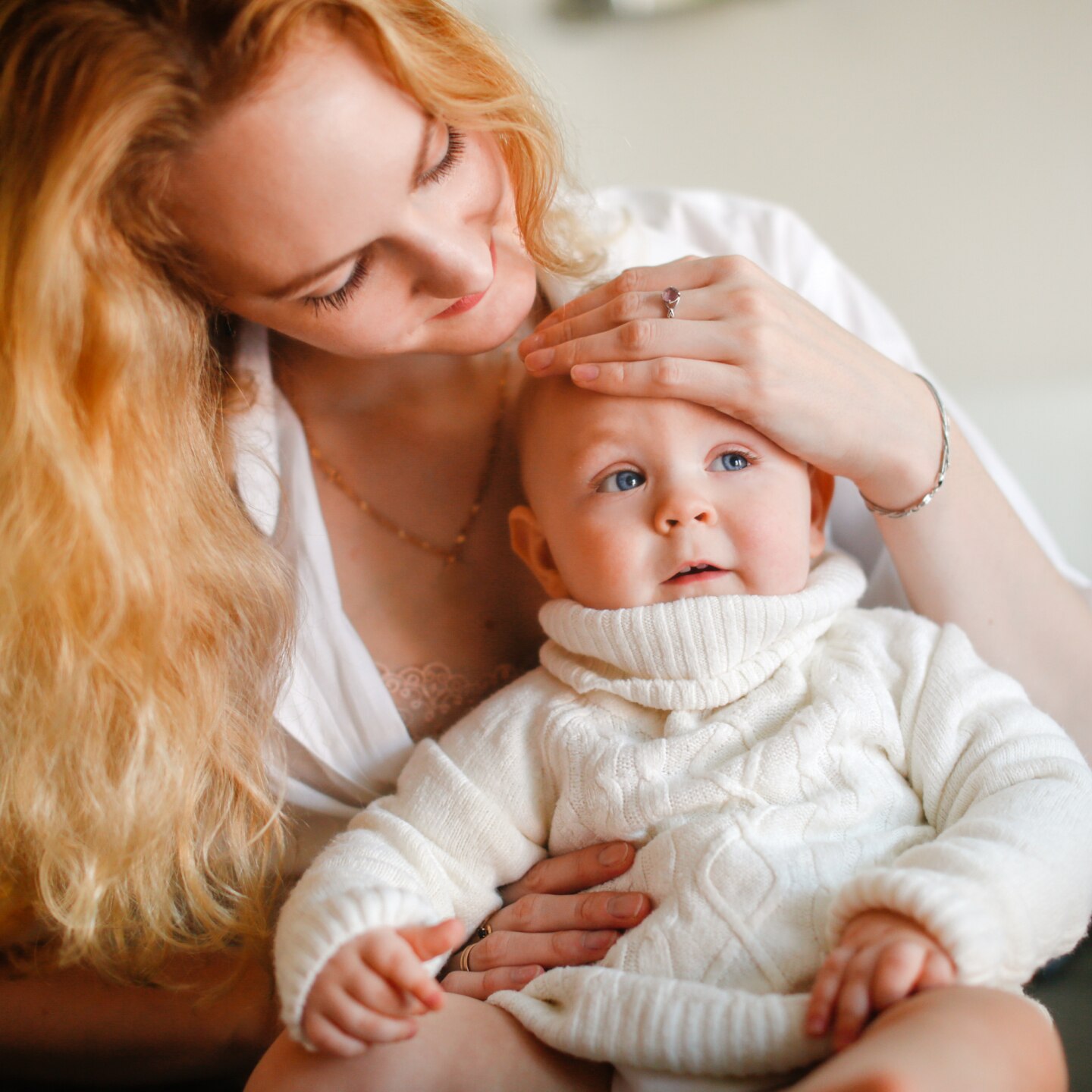 Mom touches the baby's forehead