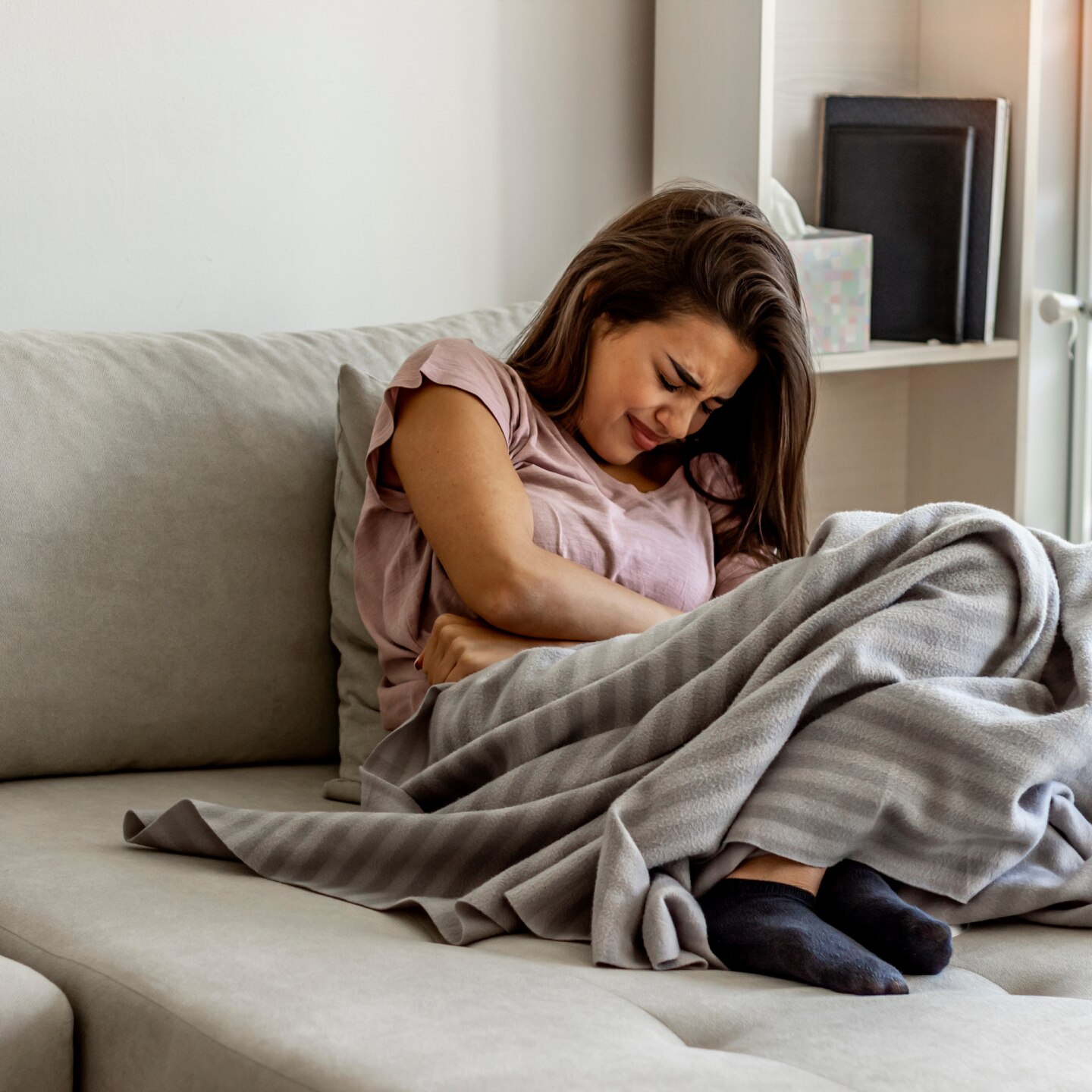 Unhappy woman holding hands on stomach suffering from abdominal pain